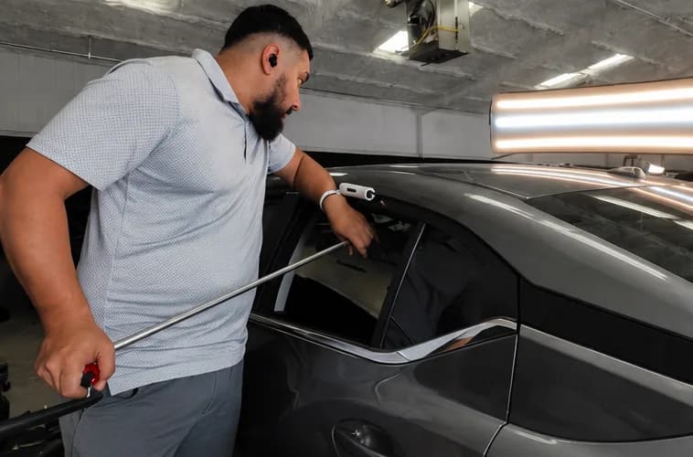 Xtreme Collision technician performing paintless dent repair on a vehicle roof in Carrollton